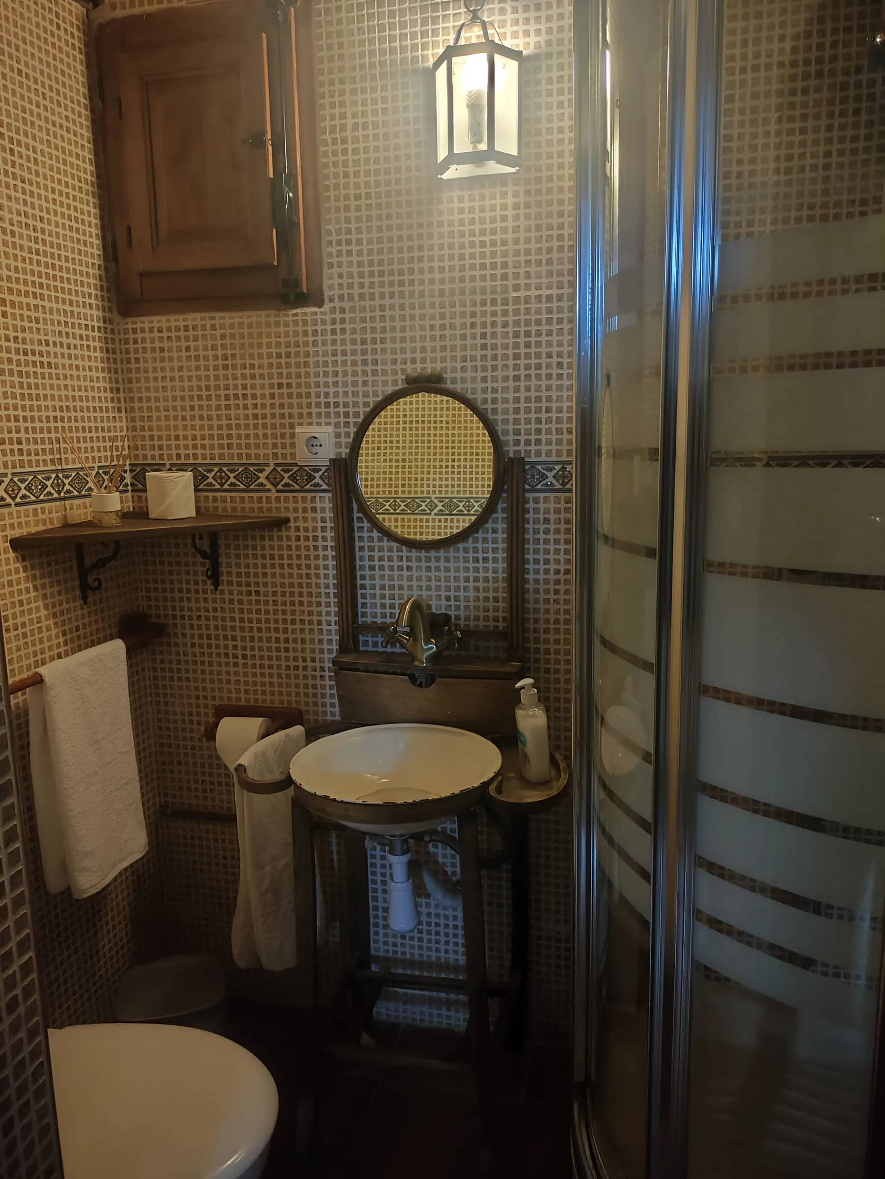 Baño con gresite, lavabo sobre mueble antiguo y ducha