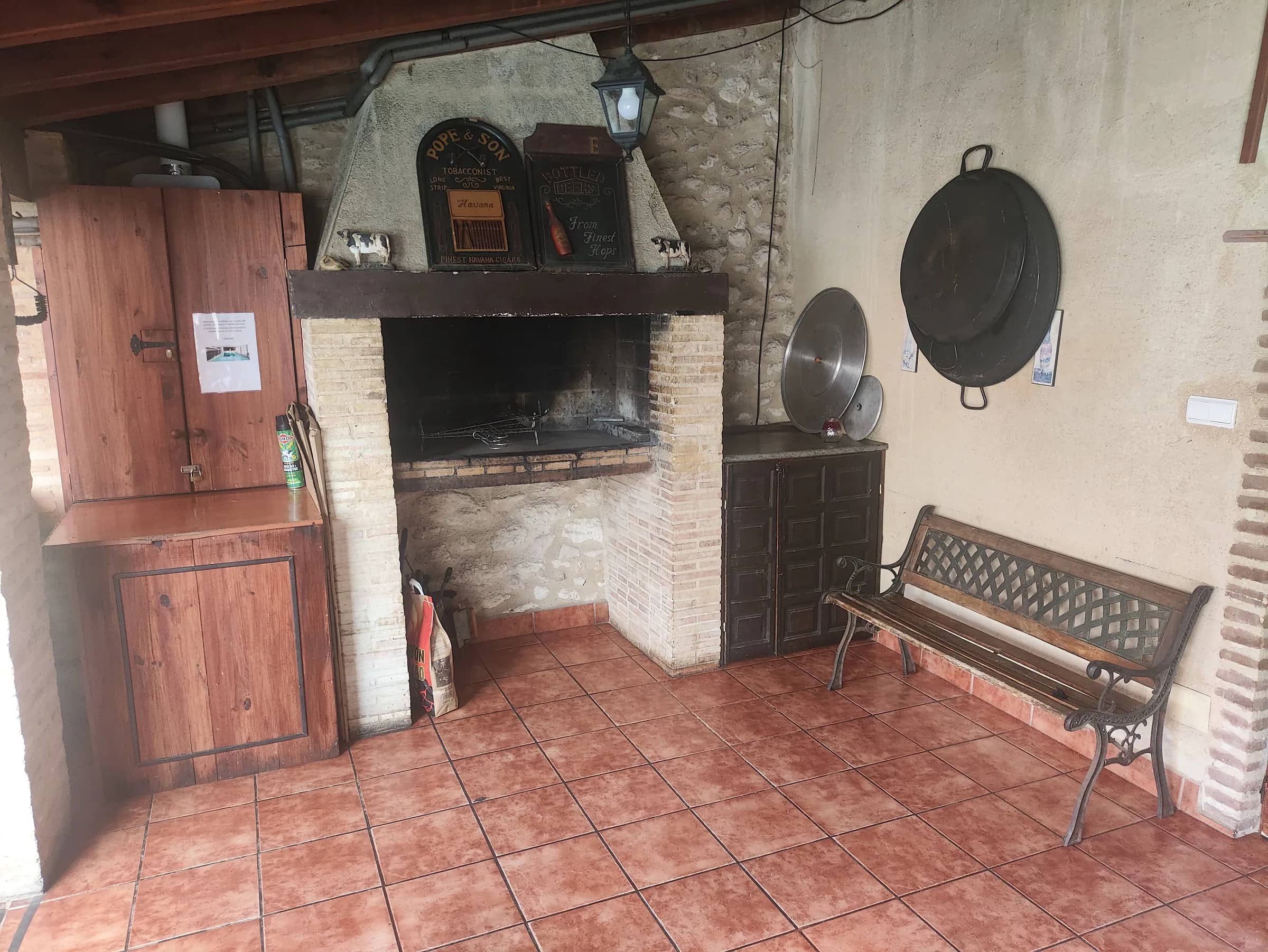 Barbacoa de leña de la casa rural con paelleras y banco de forja