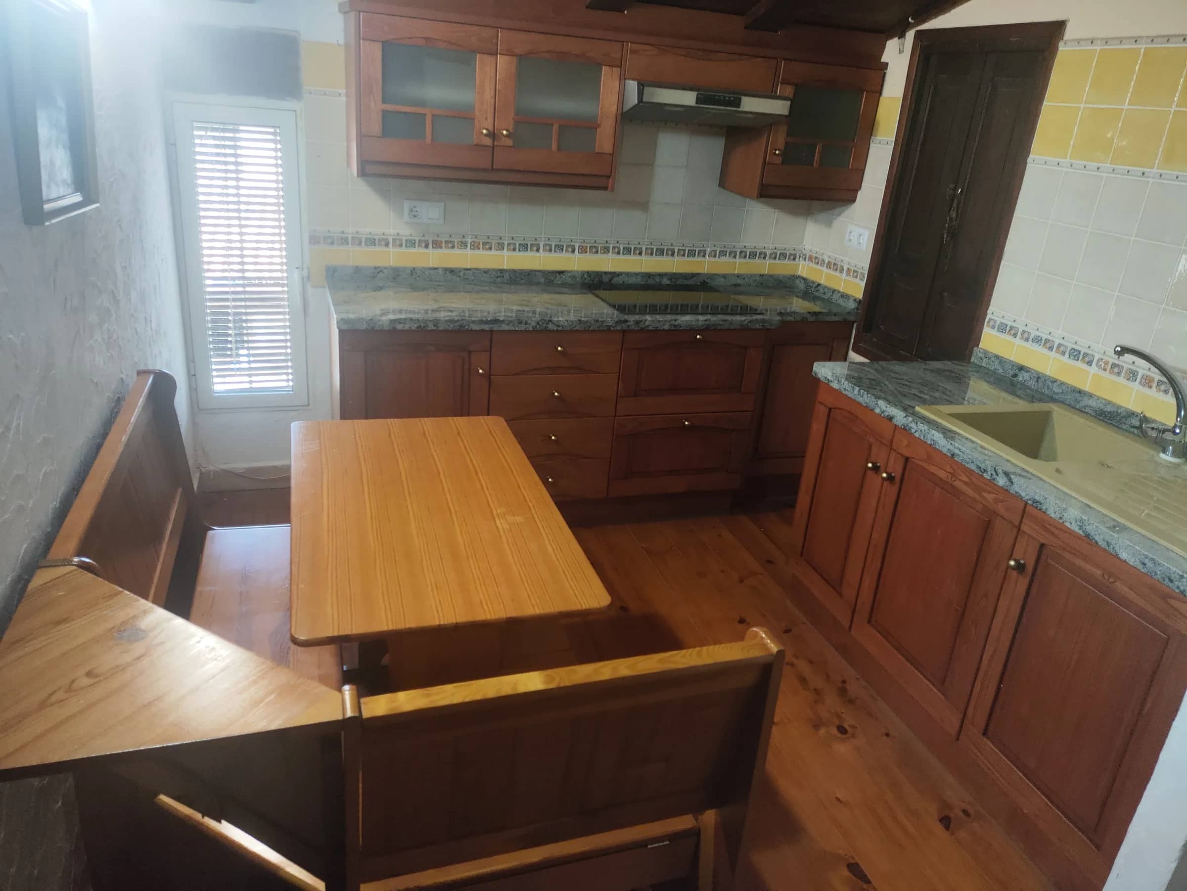 Segunda cocina de la casa rural, con encimera de mármol y mesa de madera