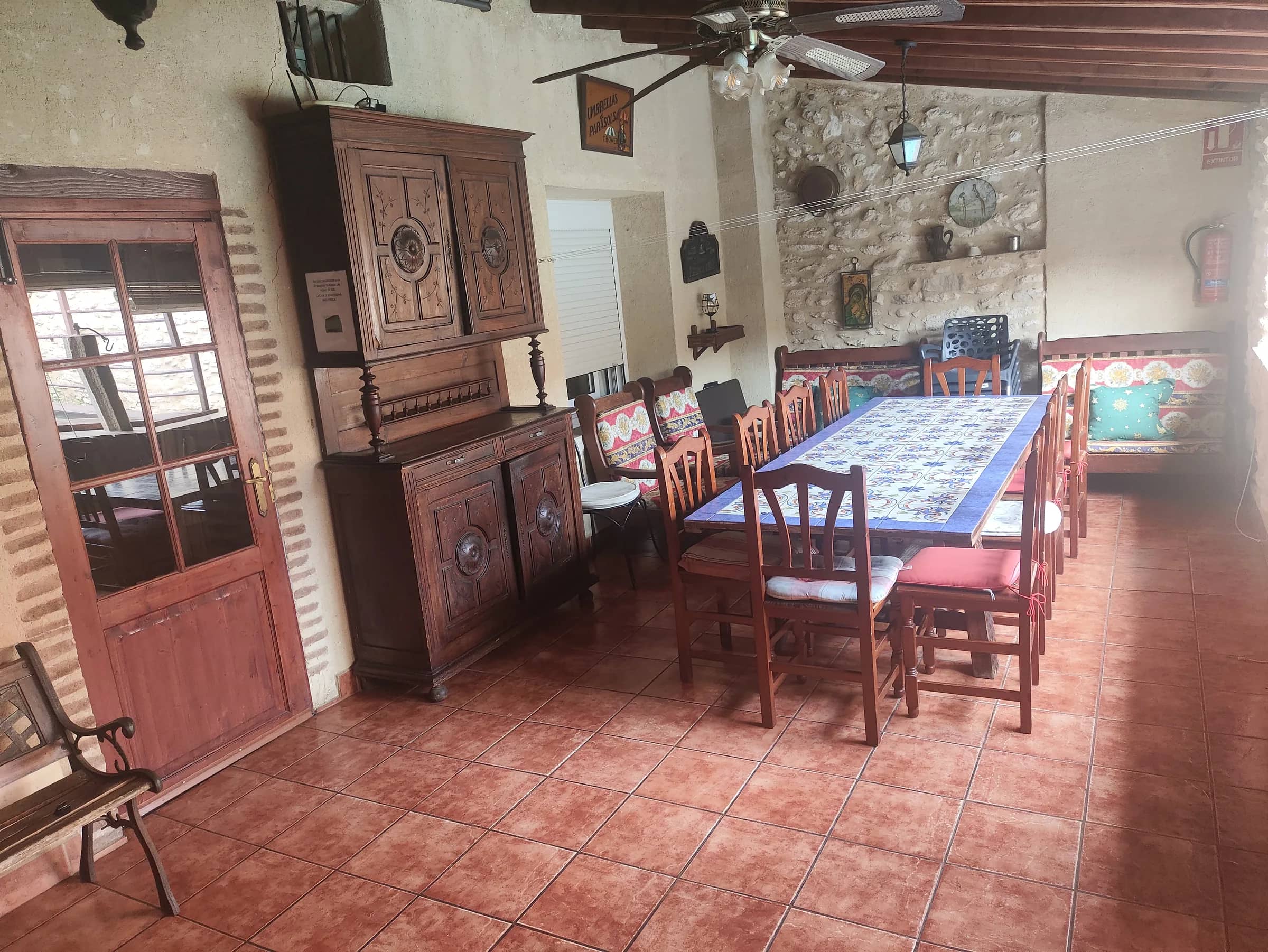 Comedor grande para grupos con bancos, aparador antiguo y pared de piedra vista