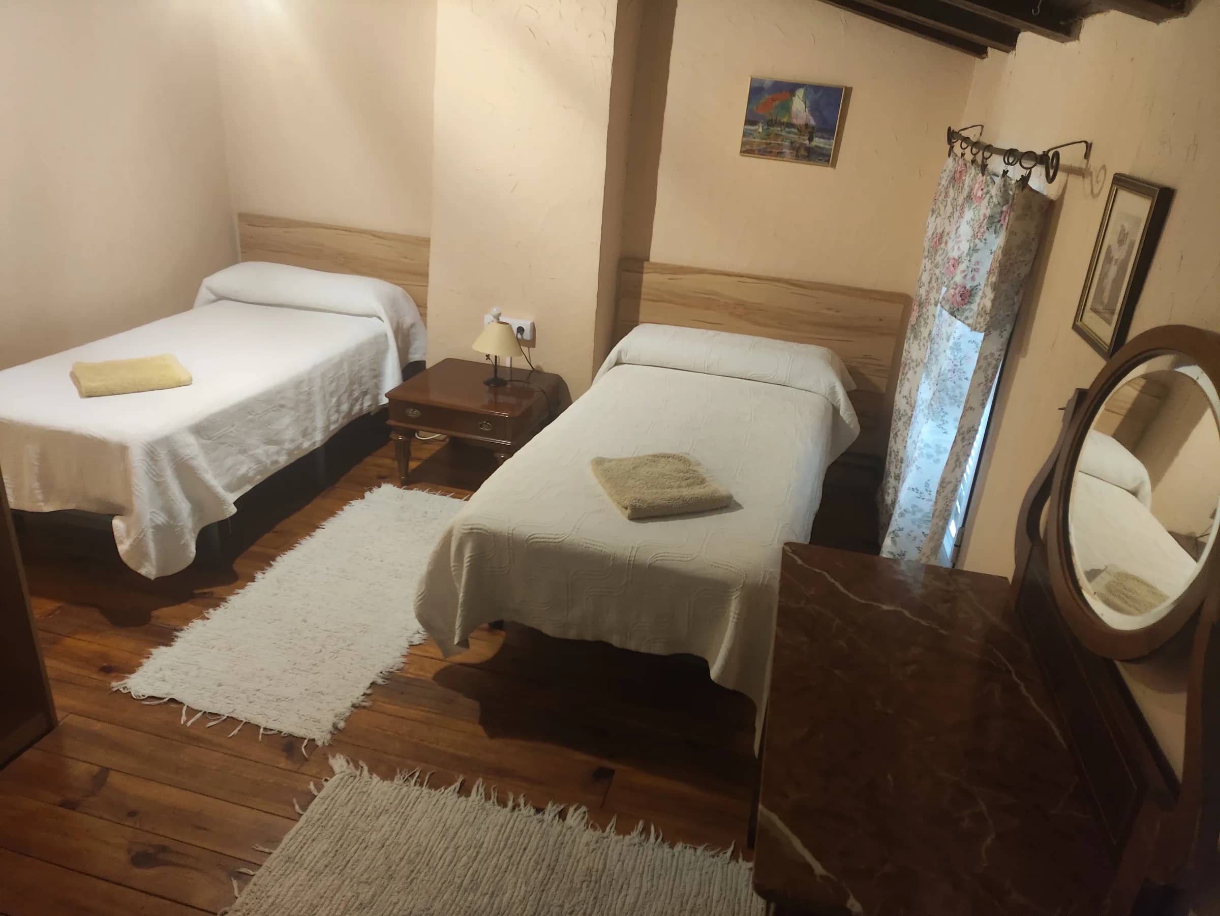Habitación abuhardillada con dos camas individuales y suelo de madera