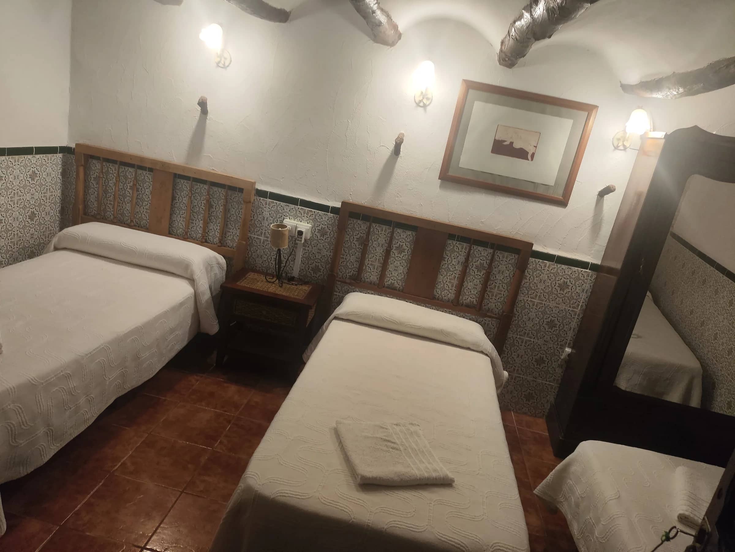 Habitación con dos camas individuales, zócalo de azulejos y vigas de madera