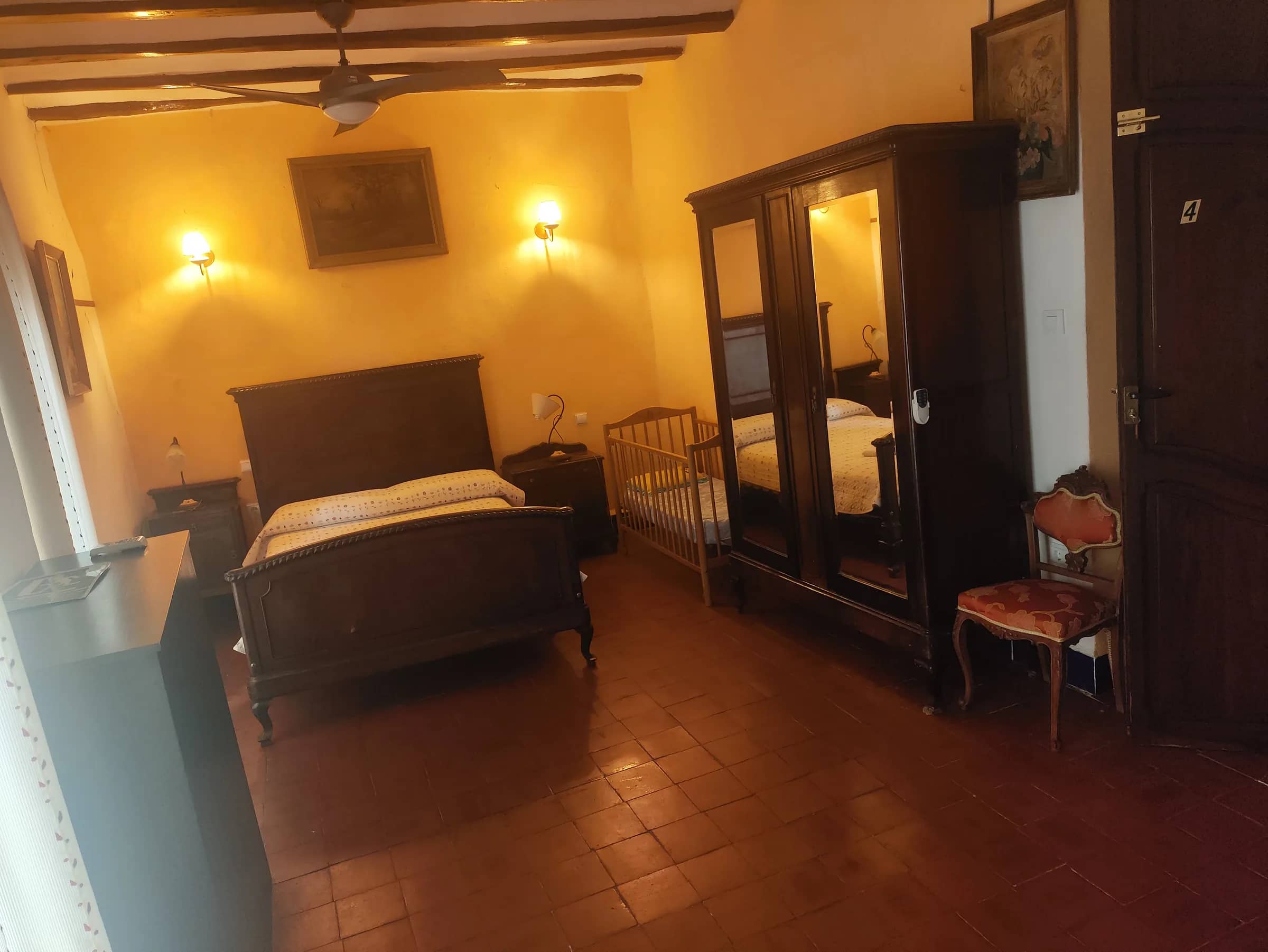 Habitación de matrimonio con cuna para bebé, armario de espejo y suelo de barro cocido